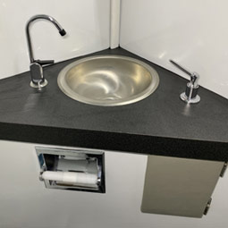 Restroom- corner sink with faucet, soap dispenser, with access door to fill soap, and toilet paper holder